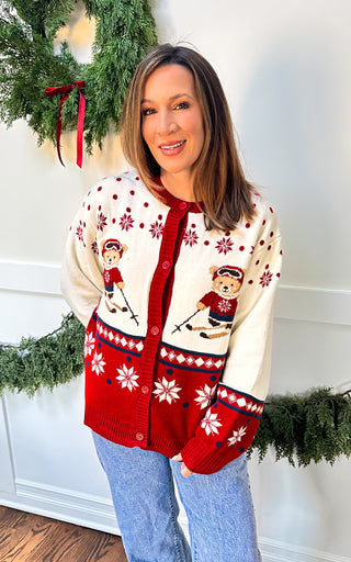 Woman wearing ivory sweater with teddy bear skiers and snowflake accents