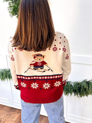Woman wearing ivory sweater with teddy bear skiers and snowflake accents