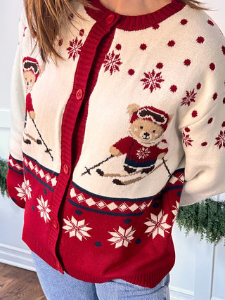 Woman wearing ivory sweater with teddy bear skiers and snowflake accents
