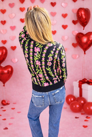 The Noir Bloom Sweater featuring pink floral vines on a black base